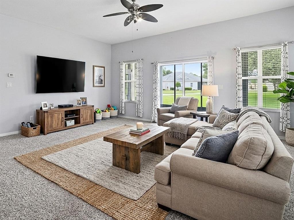 A living room features a beige sectional sofa, a wooden coffee table, and a wall-mounted television — 25509 LAUREL VALLEY ROAD, LEESBURG, FL