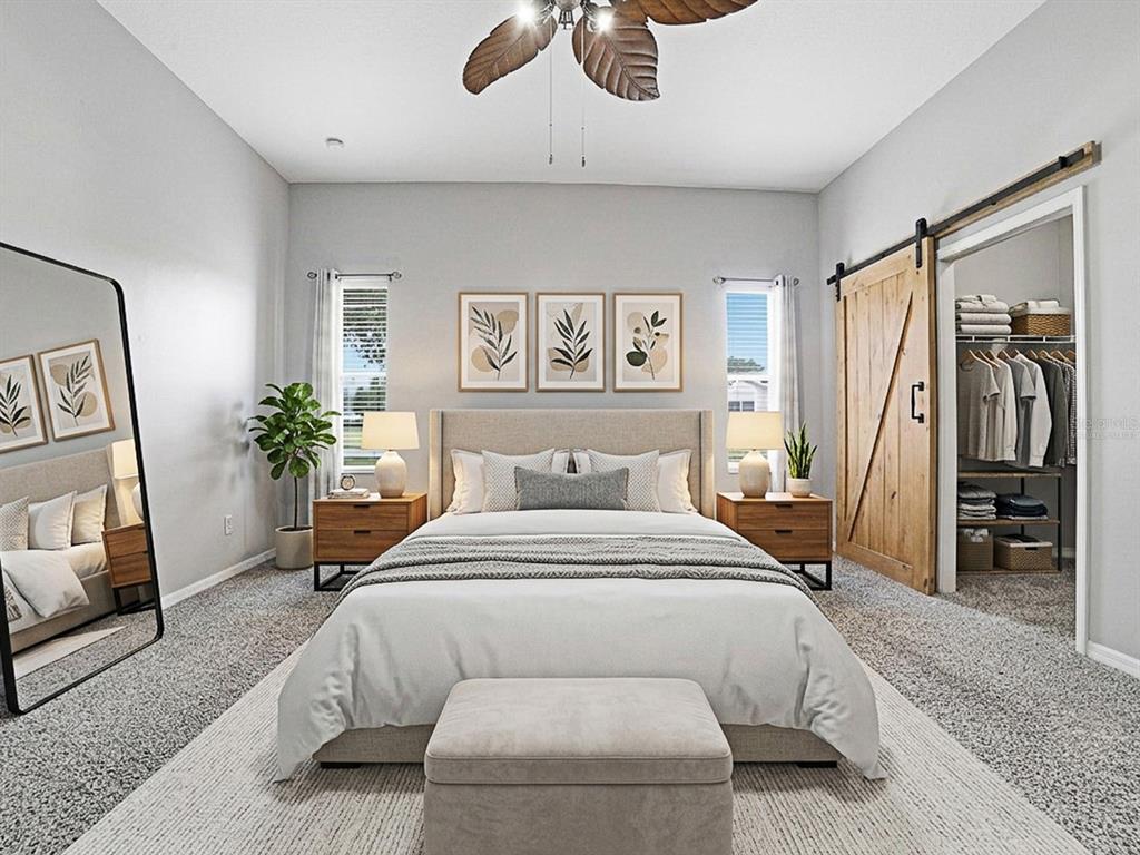 A bedroom features a bed with a neutral headboard, a sliding barn door, and a mirror — 25509 LAUREL VALLEY ROAD, LEESBURG, FL