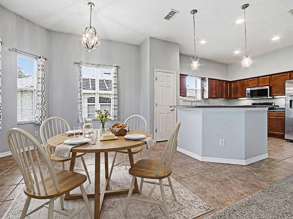 A dining area with a round wooden table sits adjacent to an open kitchen — 25509 LAUREL VALLEY ROAD, LEESBURG, FL