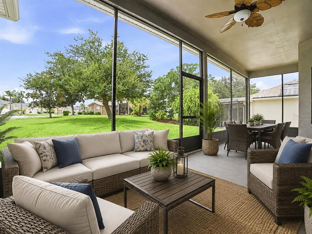 A screened-in patio features wicker furniture, a coffee table, and a view of a lawn — 25509 LAUREL VALLEY ROAD, LEESBURG, FL
