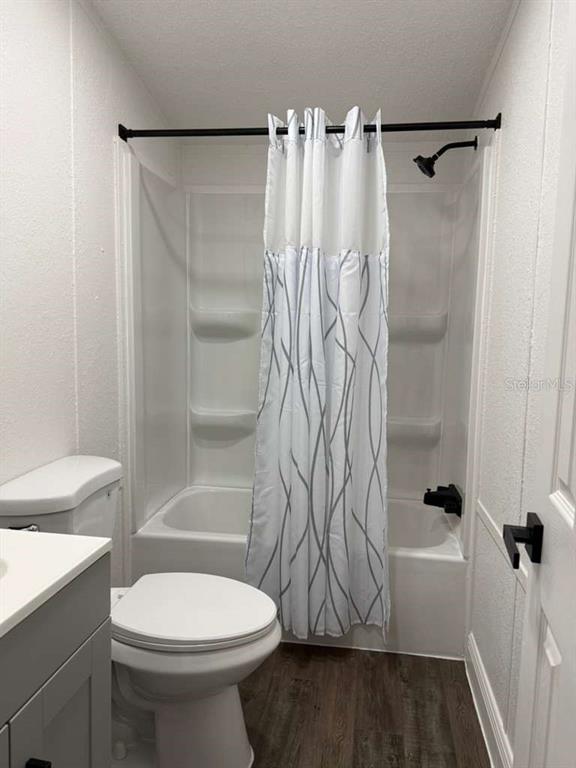 A bathroom features a white toilet, a vanity, and a shower-tub combo with a patterned curtain — 10350 EVERGREEN STREET, NEW PORT RICHEY, FL