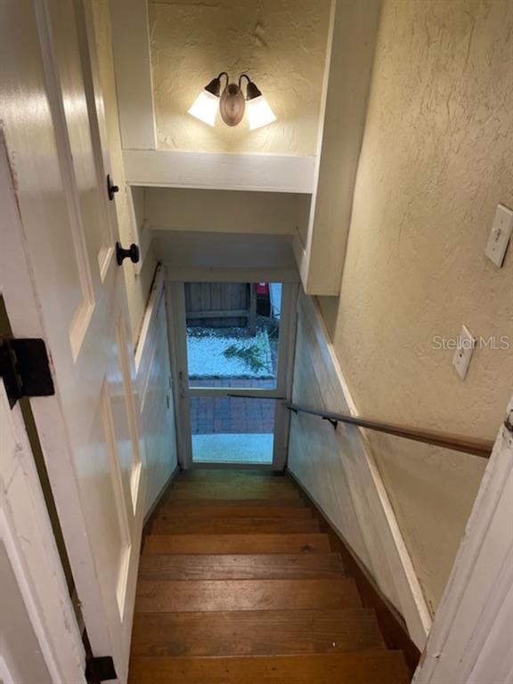A wooden staircase leads down to a glass-paned door opening to an outdoor patio — 807 1/2 S FREMONT AVENUE UNIT #Upper, TAMPA, FL