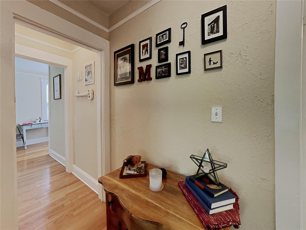 A hallway features a wooden console table, a gallery wall of framed photos, and hardwood floors — 807 1/2 S FREMONT AVENUE UNIT #Upper, TAMPA, FL