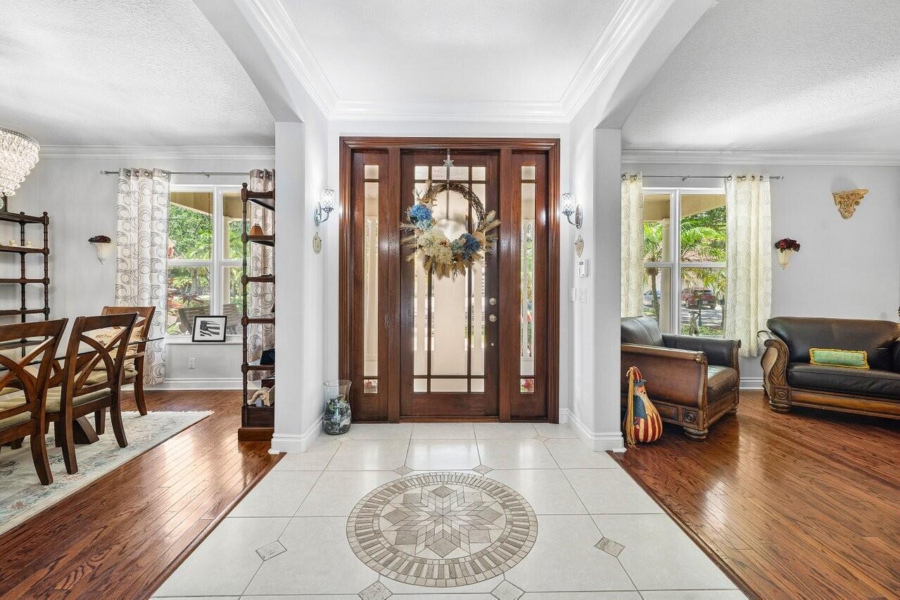 A tiled entryway leads to a wooden front door flanked by two side windows — 6990 Cypress Cove Circle, Jupiter FL 33458, JUPITER, FL