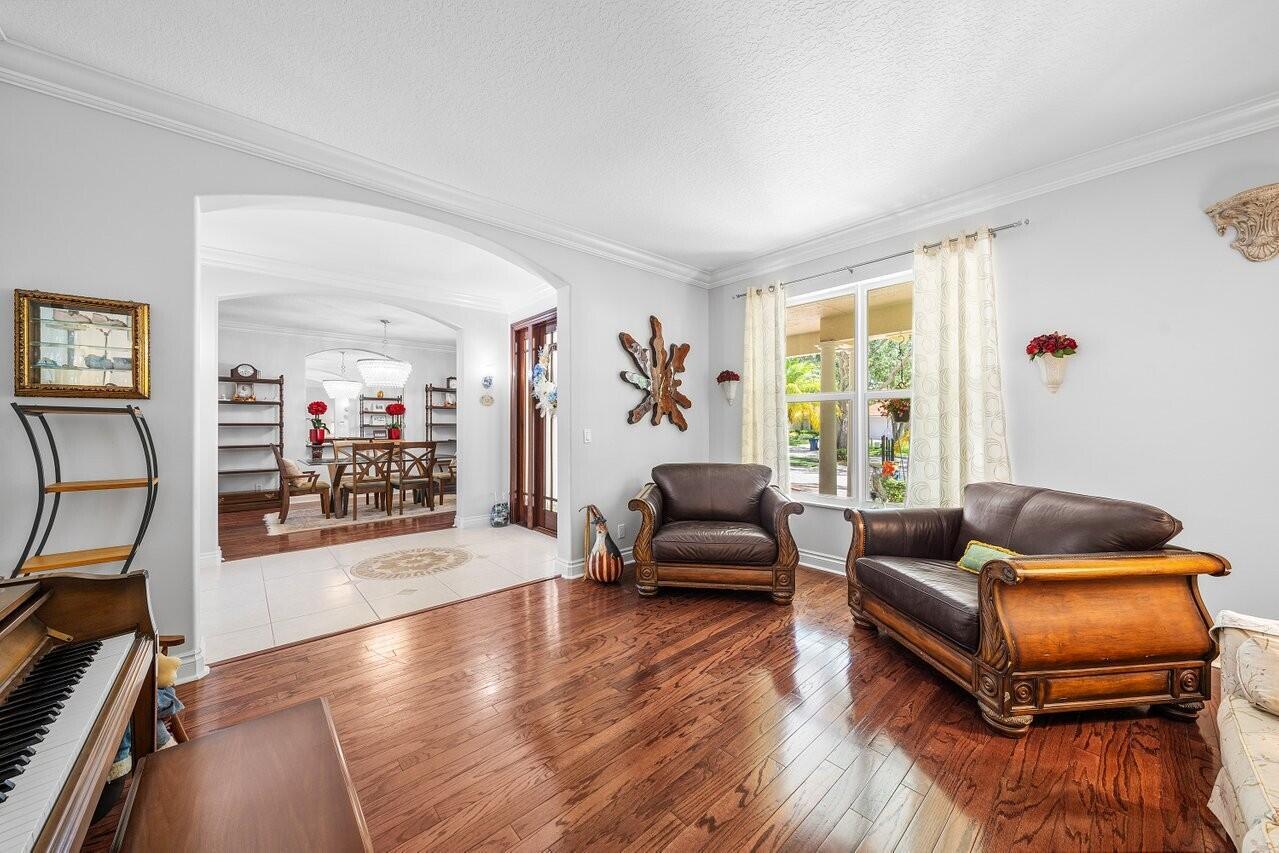 A living room with hardwood floors, leather furniture, and an arched entryway to a dining area — 6990 Cypress Cove Circle, Jupiter FL 33458, JUPITER, FL