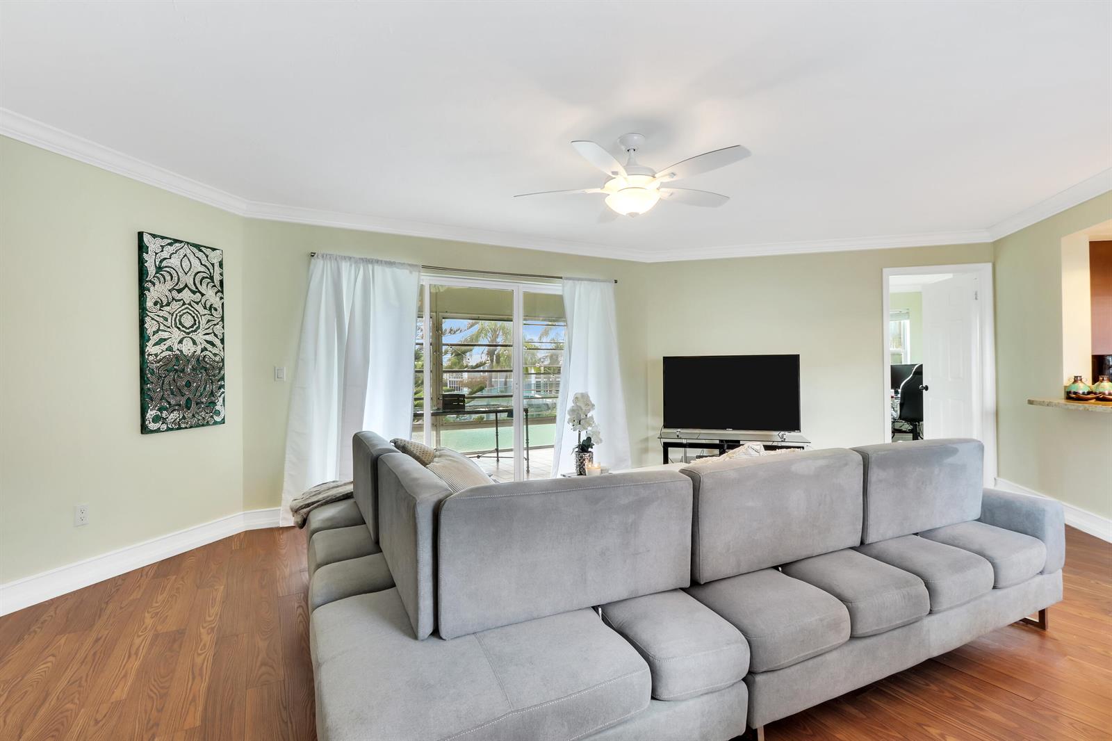 A living room features a large gray sectional sofa, wood flooring, and a sliding door — 3296 SE Aster Lane, Stuart FL 34994, STUART, FL