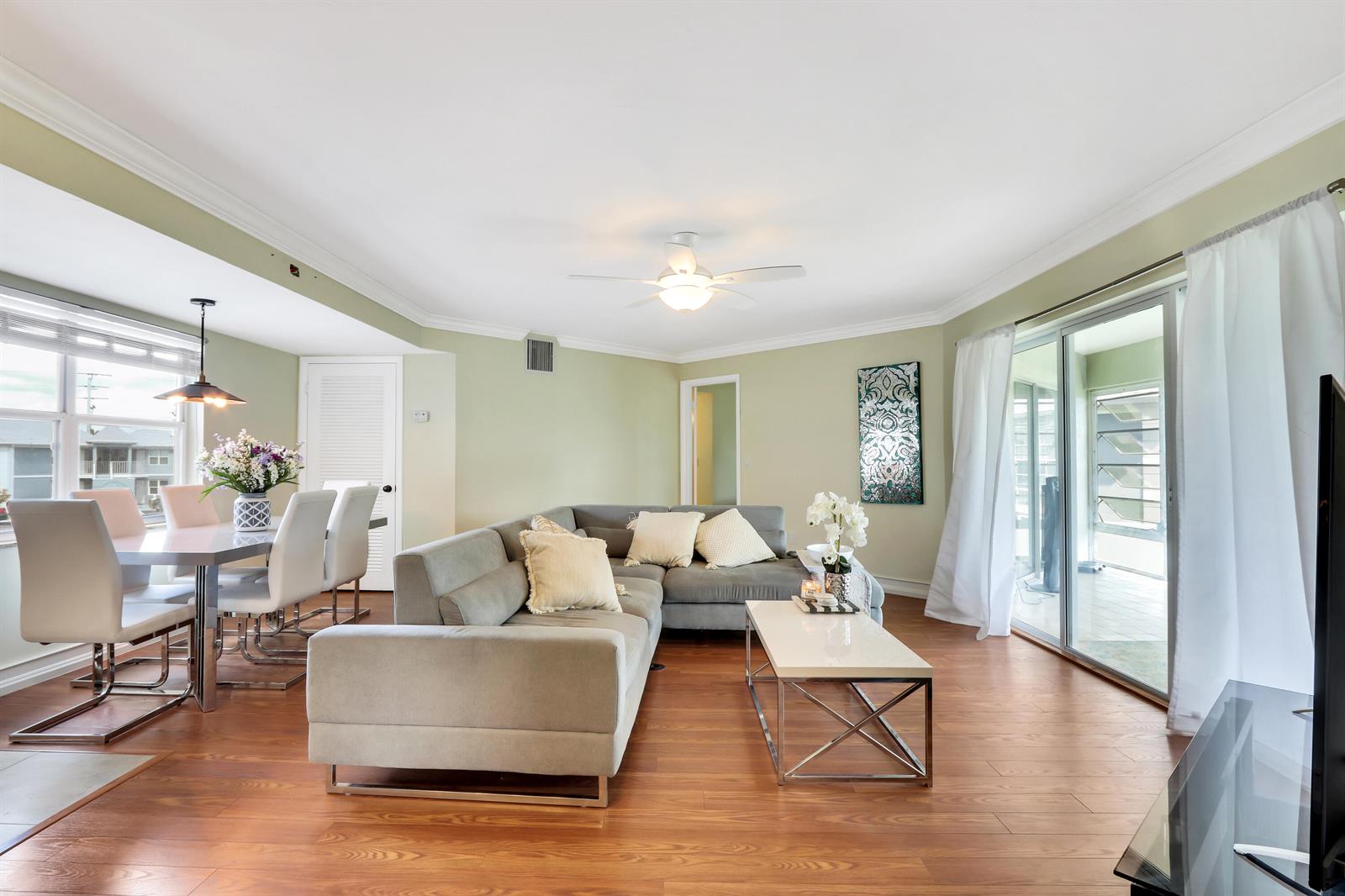 A living and dining area with light green walls, wood flooring, and a gray sectional sofa — 3296 SE Aster Lane, Stuart FL 34994, STUART, FL