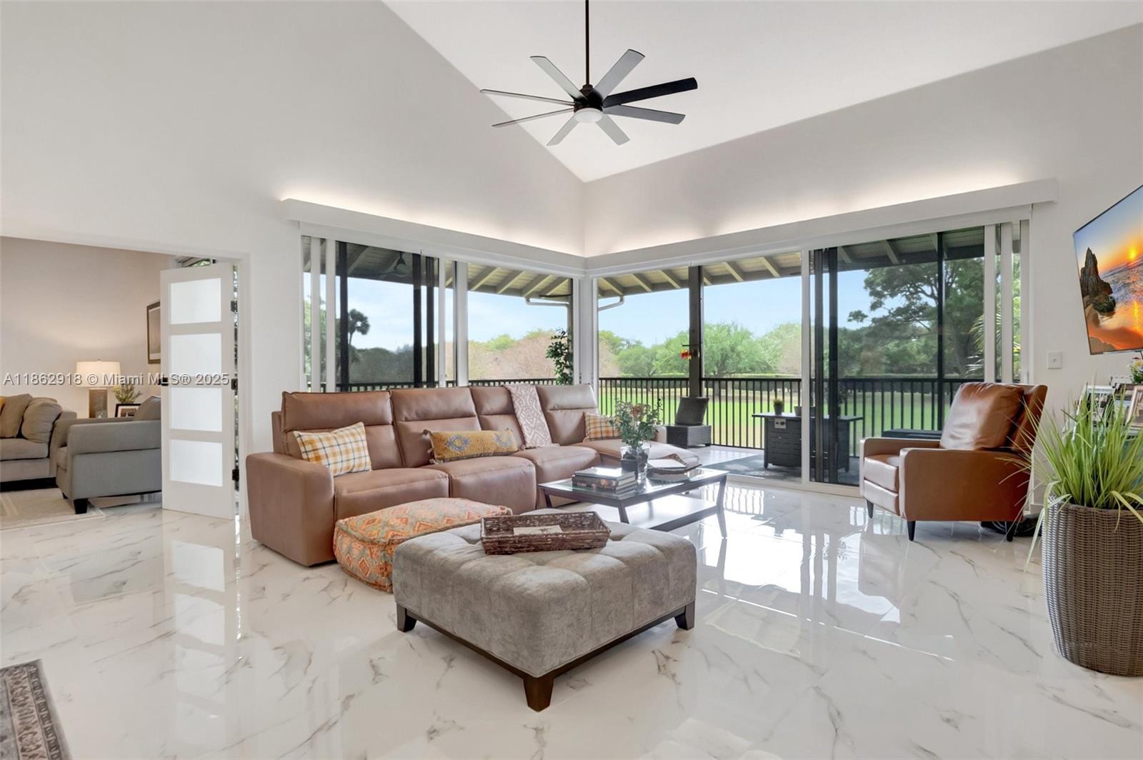A living room features white marble floors, a vaulted ceiling, and sliding glass doors to a patio — 7616 Elmridge Dr # U, Boca Raton FL 33433, BOCA RATON, FL