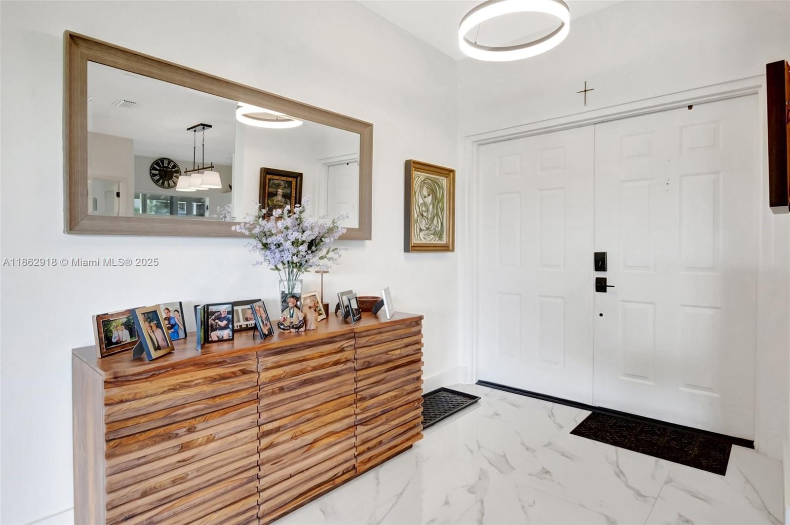 A bright entryway features a wooden console table, a large mirror, and white double doors — 7616 Elmridge Dr # U, Boca Raton FL 33433, BOCA RATON, FL