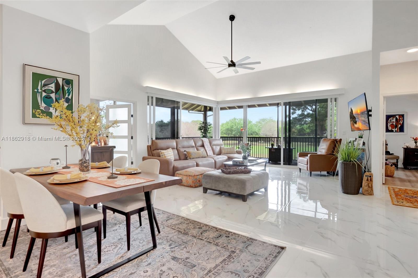 A bright open-concept living and dining area features vaulted ceilings, tile floors, and sliding glass doors — 7616 Elmridge Dr # U, Boca Raton FL 33433, BOCA RATON, FL