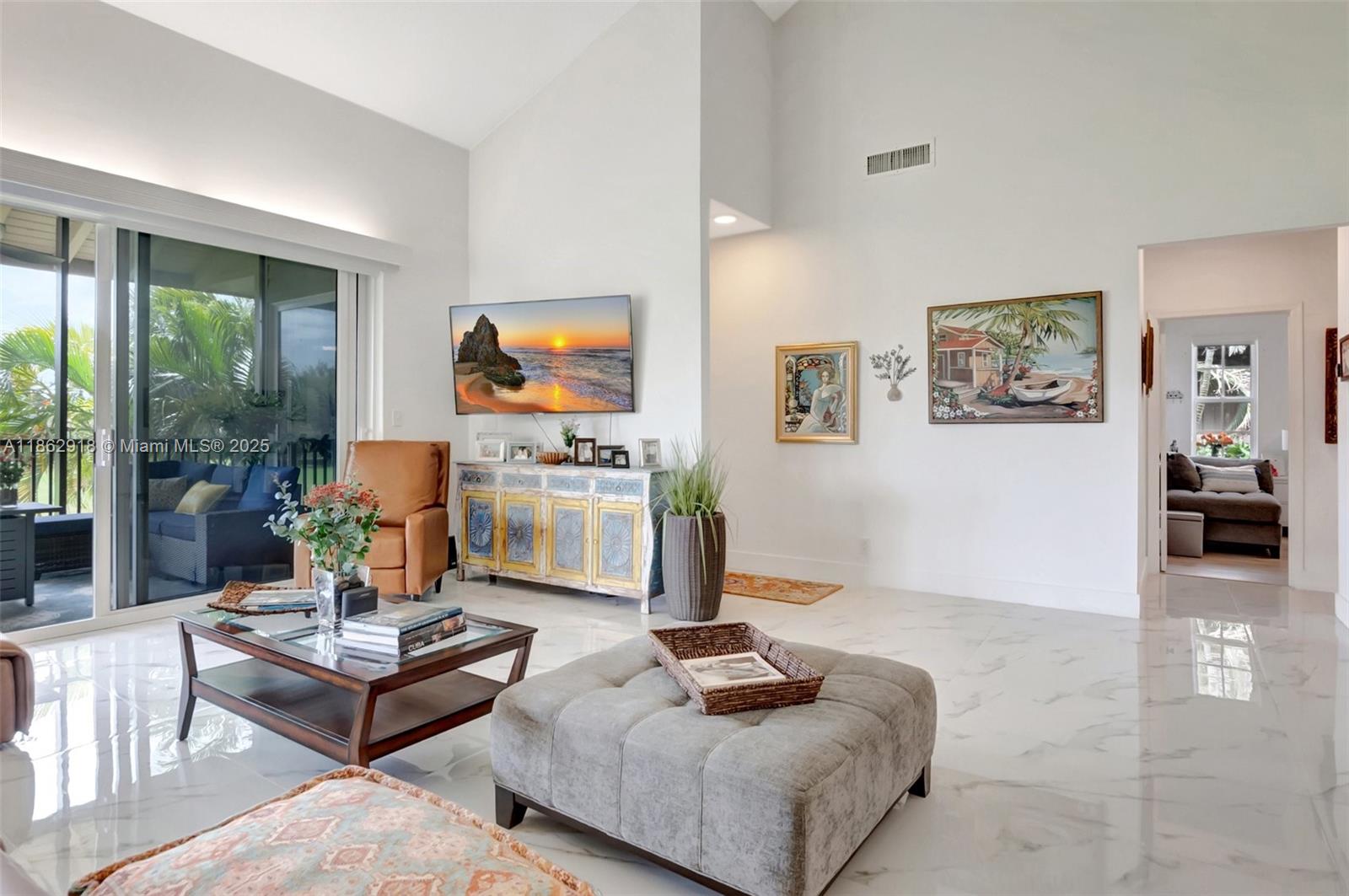 A living room features white marble floors, vaulted ceilings, a television, and a sliding glass door — 7616 Elmridge Dr # U, Boca Raton FL 33433, BOCA RATON, FL