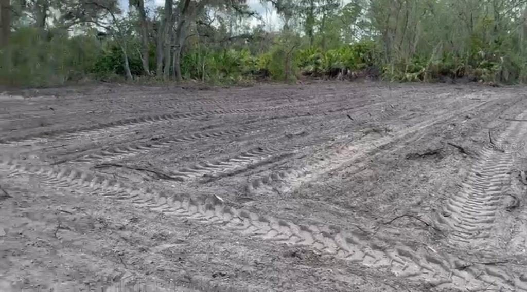 A cleared, sandy lot with heavy tire tracks leading toward a line of trees — 334 SUN COURT, LAKE PLACID, FL