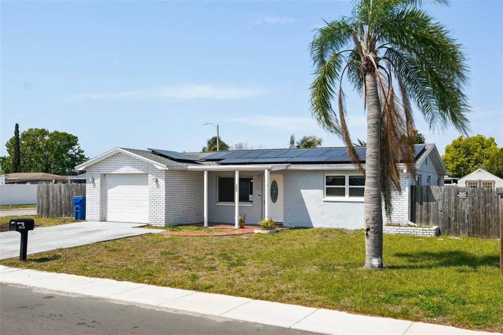 A single-story house with a white brick facade, solar panels, and a palm tree — 3207 COLDWELL DRIVE, HOLIDAY, FL
