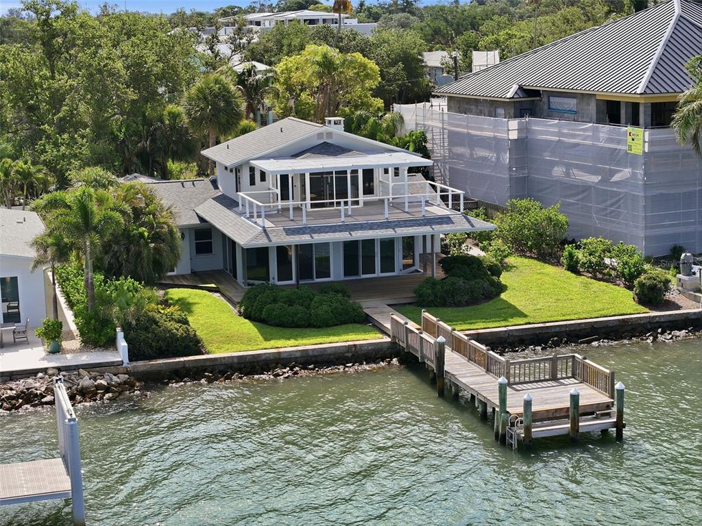 An aerial view of a two-story waterfront house with a wooden dock and deck — 1832 VENETIAN POINT DRIVE, CLEARWATER, FL