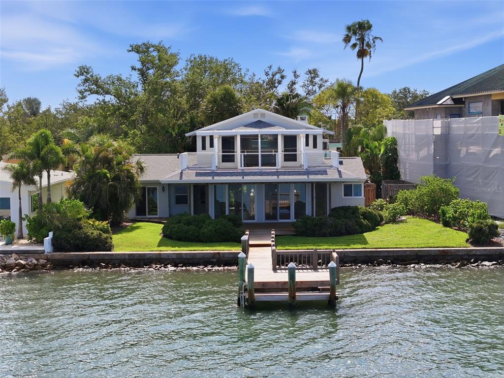 A waterfront house with a wooden dock, a screened balcony, and a grassy lawn — 1832 VENETIAN POINT DRIVE, CLEARWATER, FL