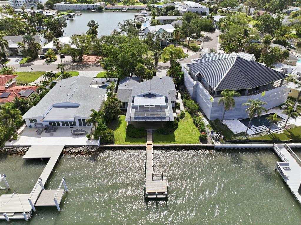 An aerial view shows three waterfront houses with private docks along a canal — 1832 VENETIAN POINT DRIVE, CLEARWATER, FL