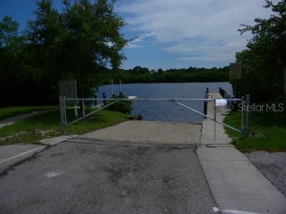 A metal gate blocks the entrance to a boat ramp leading into a lake — 5080 MONTEGO LANE, PORT CHARLOTTE, FL