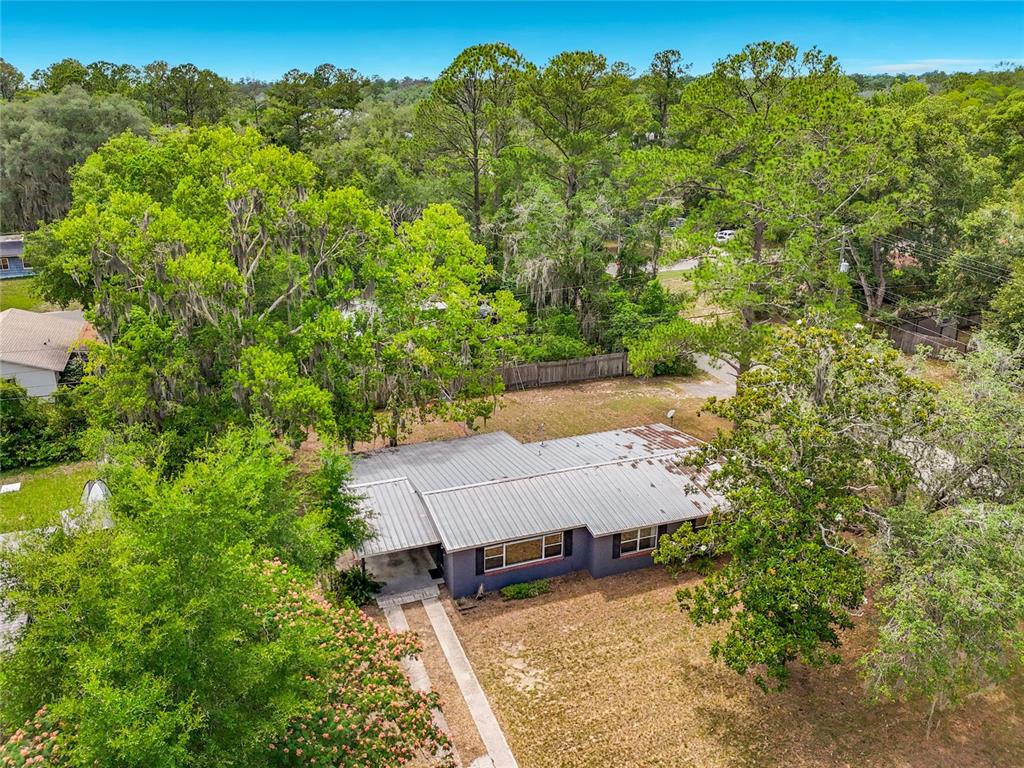 An aerial view shows a single-story house with a metal roof surrounded by mature trees — 414 NW 36TH TERRACE, GAINESVILLE, FL