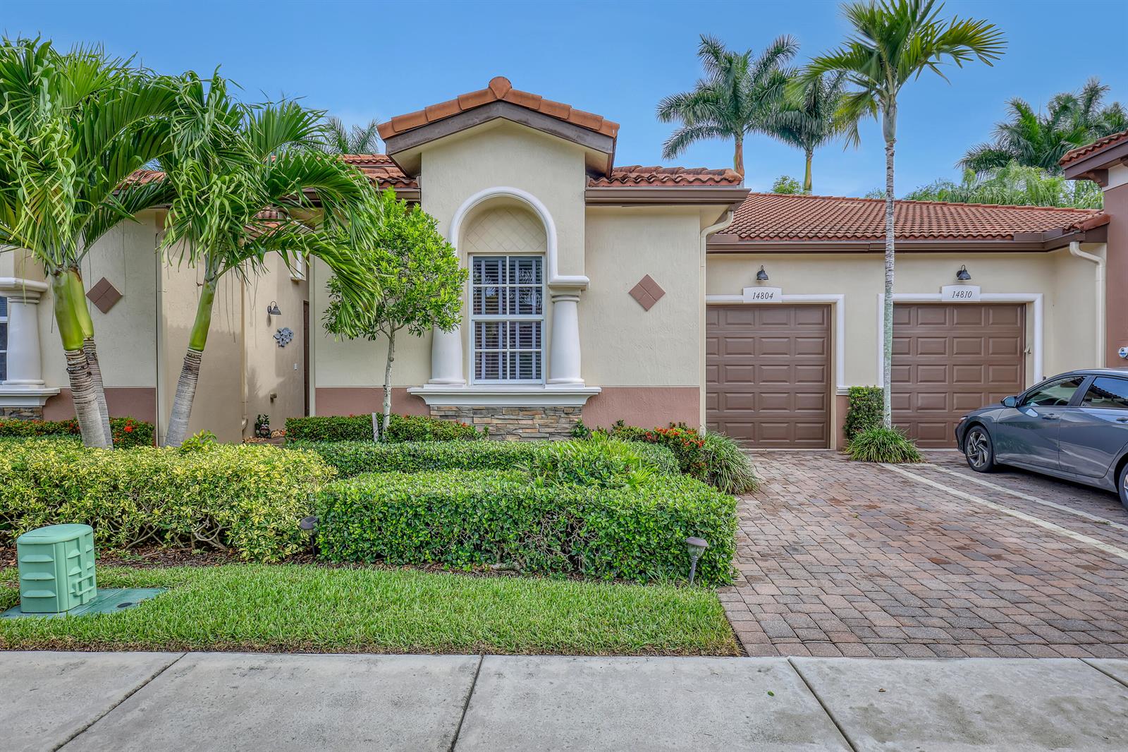 A single-story house exterior features a tiled roof, two garage doors, and landscaped front bushes — 14804 Via Porta, Delray Beach FL 33446, DELRAY BEACH, FL