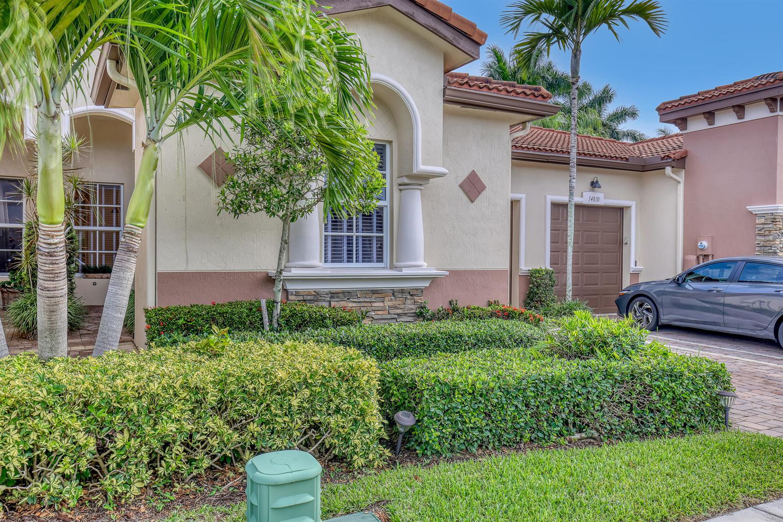 A single-story house exterior features a beige stucco facade, a brown garage door, and landscaping — 14804 Via Porta, Delray Beach FL 33446, DELRAY BEACH, FL