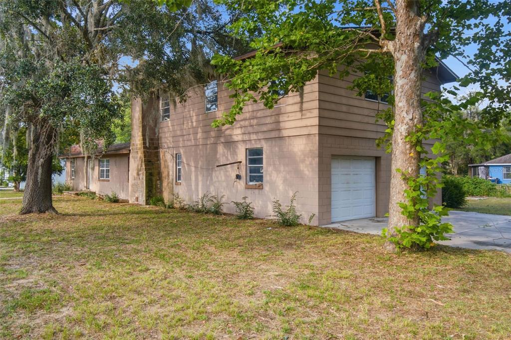 A two-story house with tan block siding, a white garage door, and surrounding trees — 2805 NE 24TH COURT, OCALA, FL