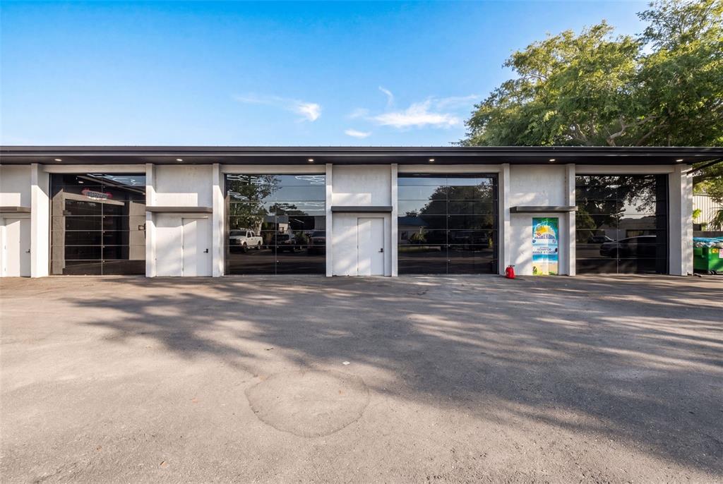 The exterior of a commercial building features four glass garage doors and two entry doors — 501 INTERSTATE COURT, SARASOTA, FL