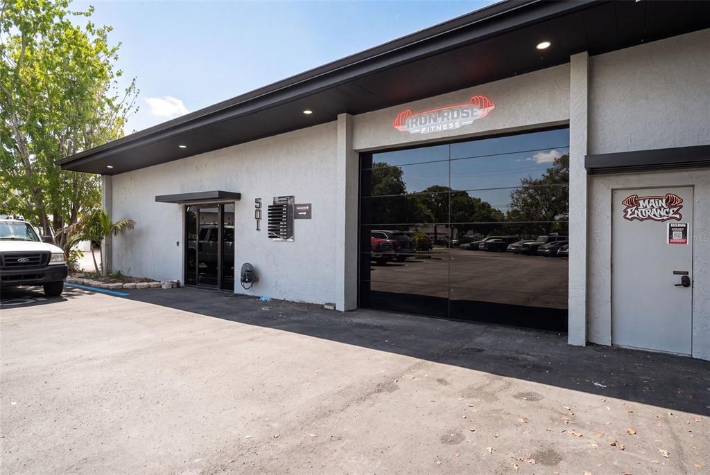 The exterior of a commercial building features a glass garage door and a main entrance — 501 INTERSTATE COURT, SARASOTA, FL