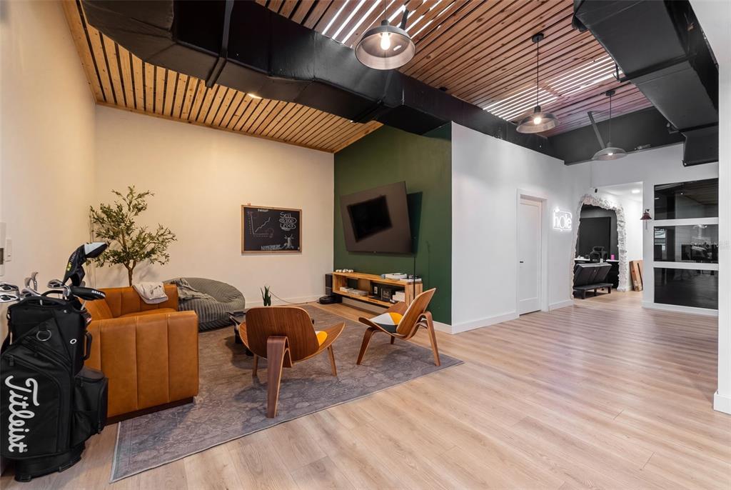 A modern lounge area features wood-slat ceilings, a green accent wall, and mid-century modern furniture — 501 INTERSTATE COURT, SARASOTA, FL