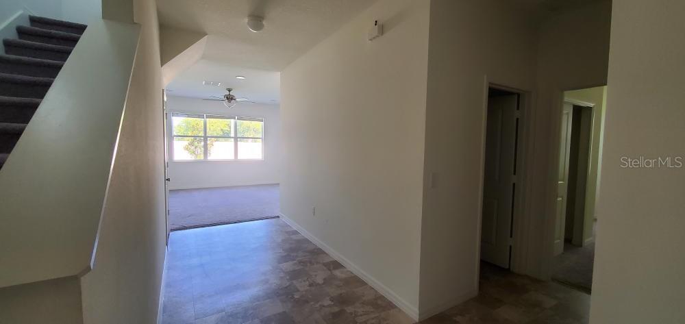 A hallway with tile flooring leads toward a carpeted living area with large windows — 2354 TWIN FLOWER LANE, SANFORD, FL