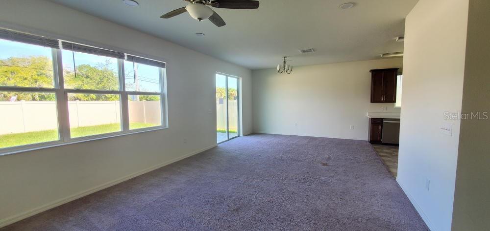 A carpeted living room features a ceiling fan, large windows, and a sliding glass door — 2354 TWIN FLOWER LANE, SANFORD, FL