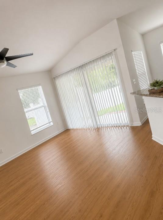 A living room with wood-look flooring, a ceiling fan, a window, and sliding glass doors — 7249 TWIN CEDAR LANE, LAKELAND, FL