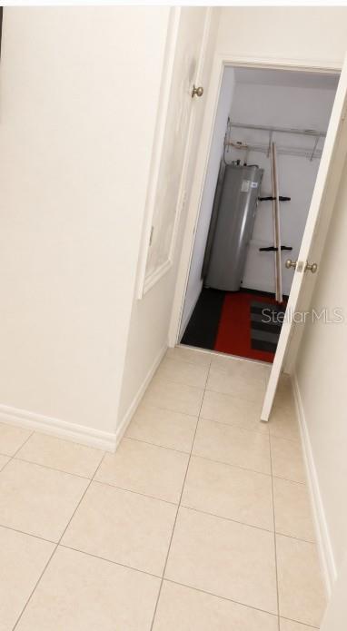 A tiled hallway leads to a utility closet containing a water heater and shelving — 7249 TWIN CEDAR LANE, LAKELAND, FL