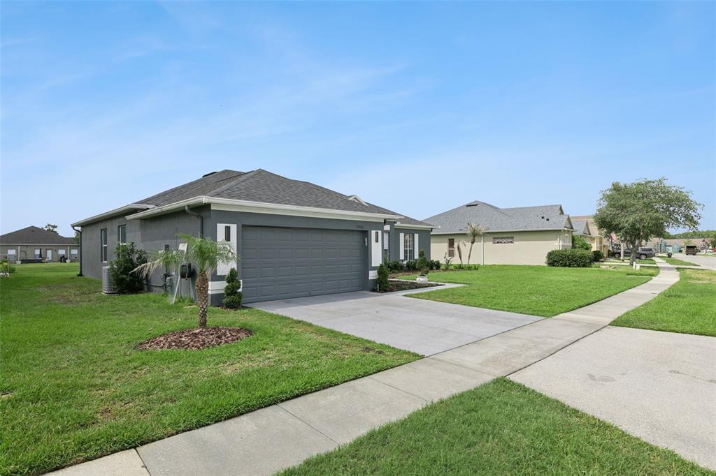 A gray single-story house with a two-car garage and a green lawn — 13606 SUMMER RAIN DRIVE, ORLANDO, FL