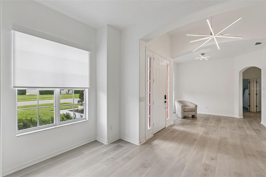 An entryway with light wood flooring, a white front door, and a modern starburst chandelier — 13606 SUMMER RAIN DRIVE, ORLANDO, FL