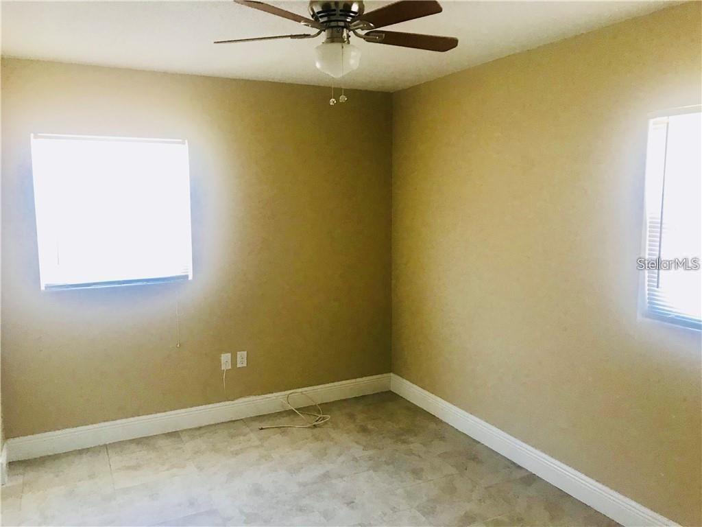 An empty bedroom features tan walls, tile flooring, and a ceiling fan — 23 COLLEGE DRIVE, BABSON PARK, FL