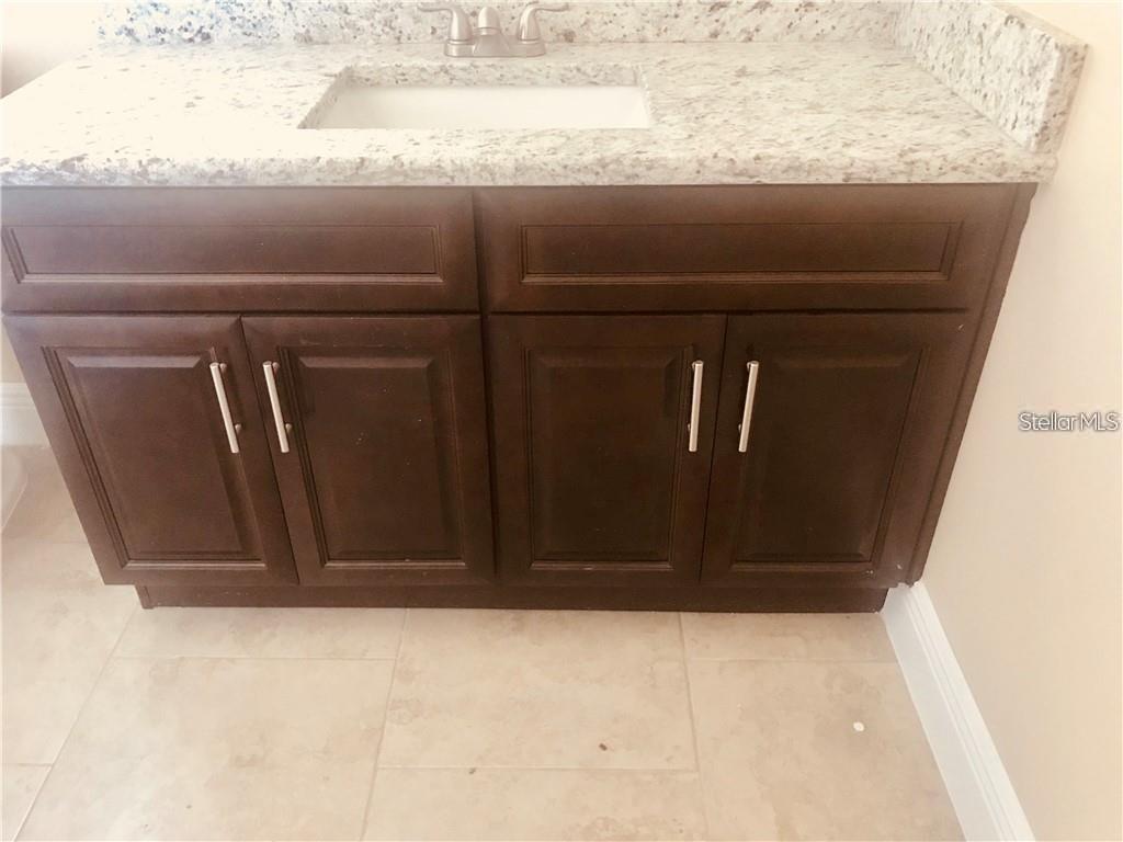 A bathroom vanity features a speckled granite countertop, a white sink, and dark wood cabinets — 23 COLLEGE DRIVE, BABSON PARK, FL