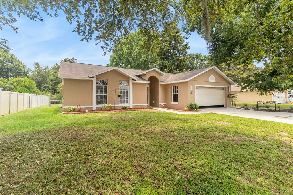 A single-story tan house with a two-car garage and a large front lawn — 1564 CYPRESS WOODS CIRCLE, ST CLOUD, FL