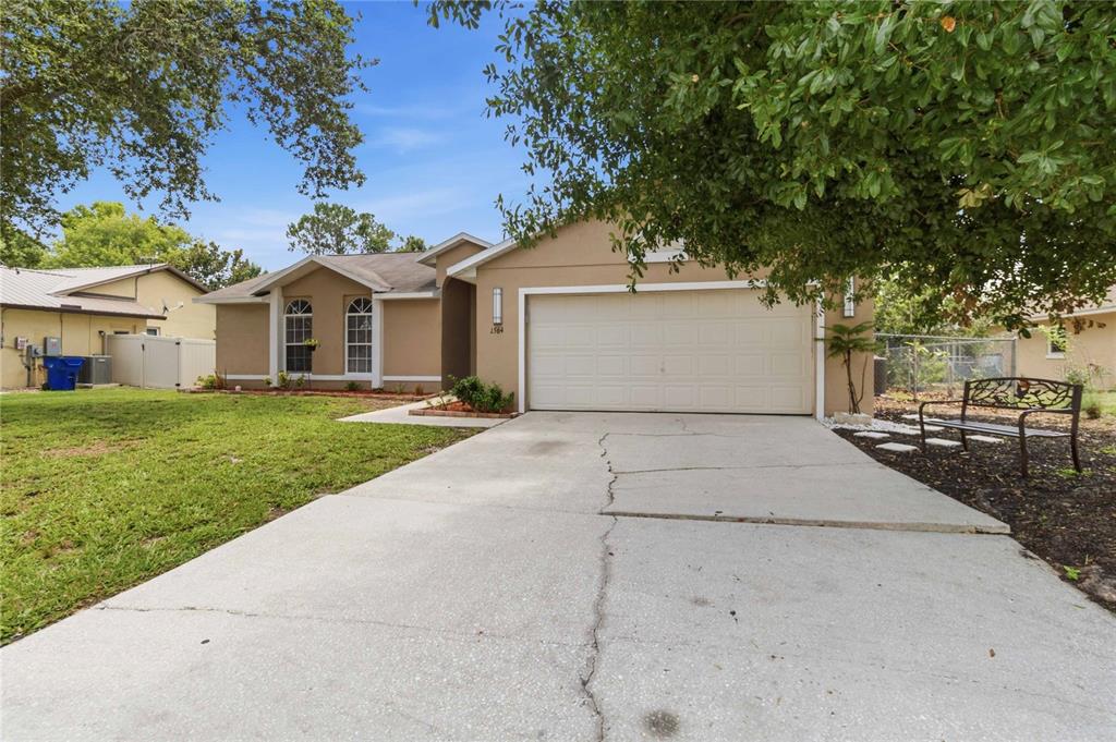 A tan single-story house with a two-car garage, concrete driveway, and a front yard — 1564 CYPRESS WOODS CIRCLE, ST CLOUD, FL