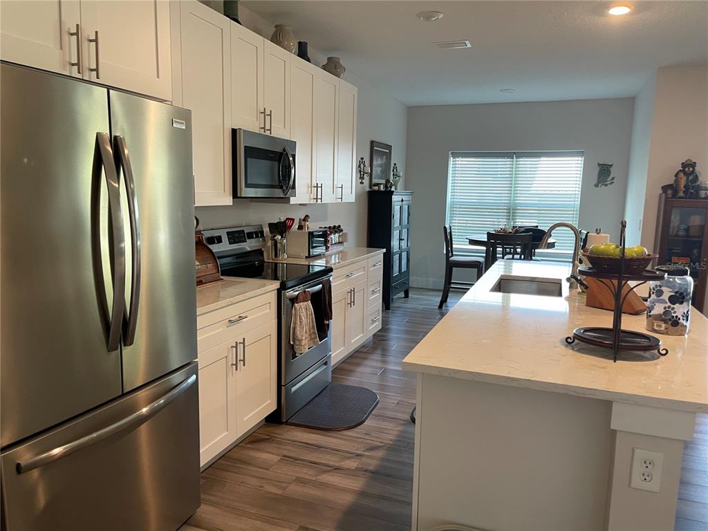 A kitchen features white cabinets, stainless steel appliances, and a large island with a sink — 13084 MOTMOT ROAD, WEEKI WACHEE, FL