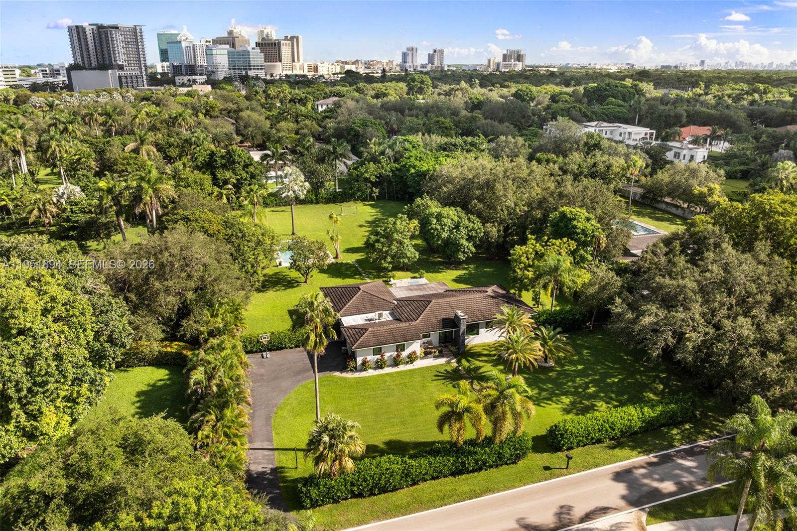 An aerial view shows a single-story house with a dark roof surrounded by lush trees — 07325 SW 102nd St, Pinecrest FL 33156, PINECREST, FL