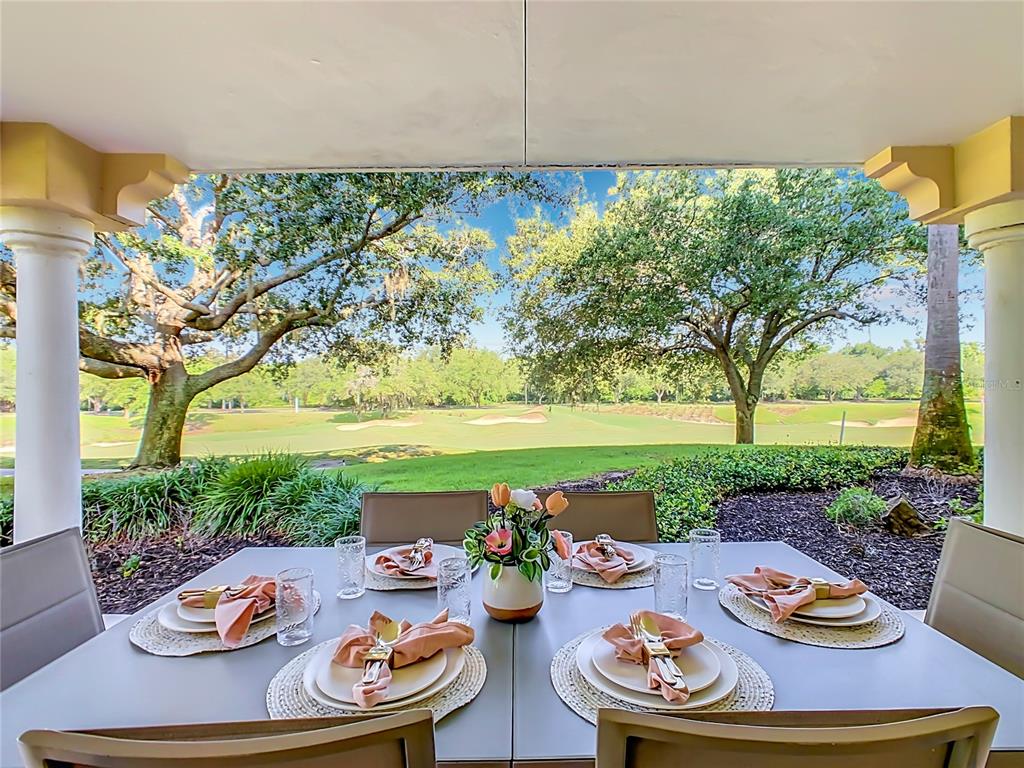 A patio dining table is set for four overlooking a golf course and trees — 1358 CENTRE COURT RIDGE DRIVE UNIT 101, REUNION, FL