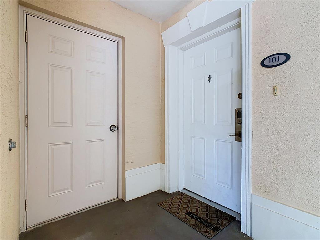 Two white doors are set into a beige exterior wall, with unit number 101 displayed — 1358 CENTRE COURT RIDGE DRIVE UNIT 101, REUNION, FL