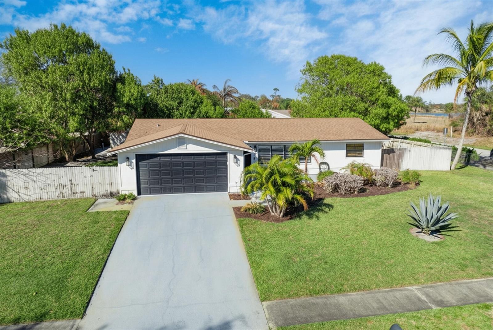 An aerial view of a single-story house with a brown roof, white siding, and garage — 221 Caprol Lane, Sebastian FL 32958, SEBASTIAN, FL