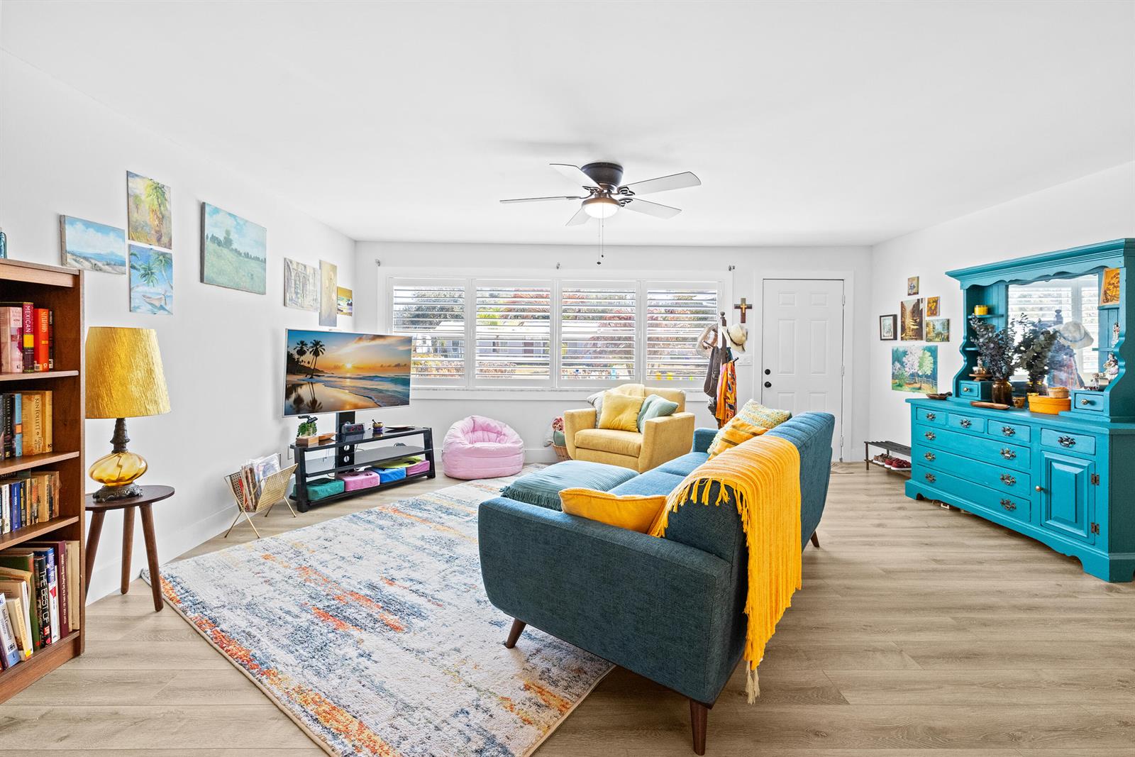 A living room features a blue sofa, a yellow armchair, a television, and a hutch — 221 Caprol Lane, Sebastian FL 32958, SEBASTIAN, FL