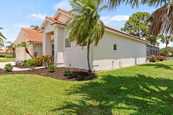 A side view of a beige stucco house with a tiled roof and palm tree — 8753 MERION AVENUE, SARASOTA, FL