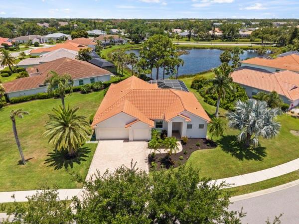 An aerial view shows a single-story house with a tile roof near a lake — 8753 MERION AVENUE, SARASOTA, FL
