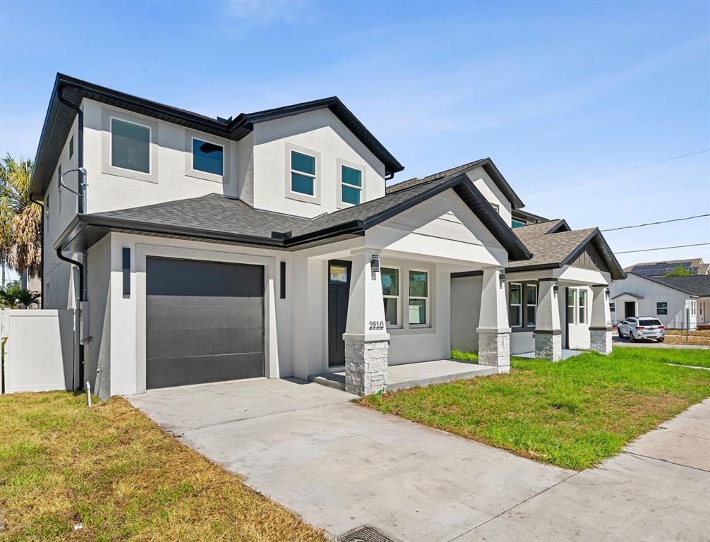 A two-story house with a white stucco exterior, a single-car garage, and a covered porch — 2910 N 21ST STREET, TAMPA, FL