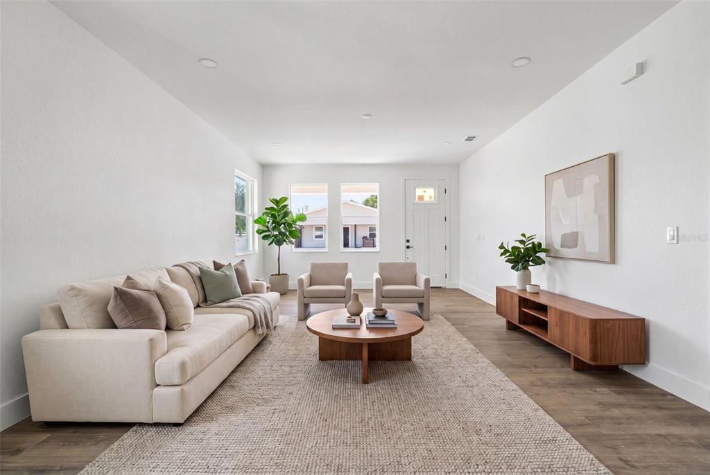 A bright living room features a beige sofa, two armchairs, a wooden coffee table, and console — 2910 N 21ST STREET, TAMPA, FL