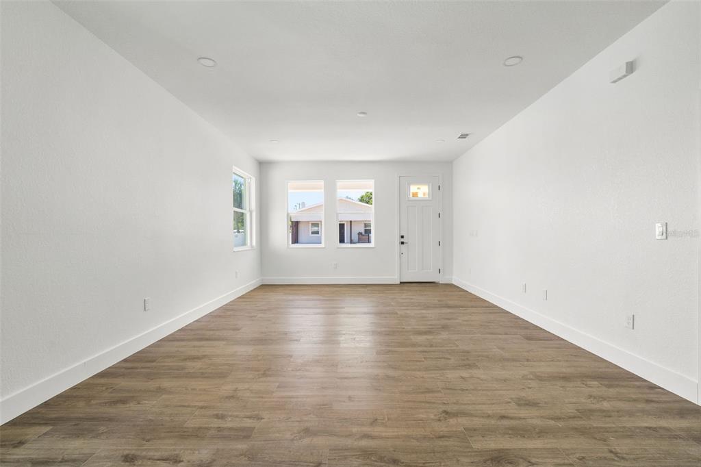 An empty living room features white walls, recessed lighting, and wood-look flooring — 2910 N 21ST STREET, TAMPA, FL