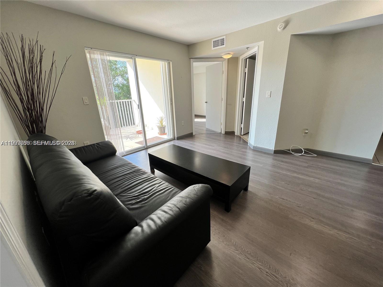 A living room features a black sofa, a coffee table, and a sliding glass door — 637 SW 3rd St # 306, Miami FL 33130, MIAMI, FL